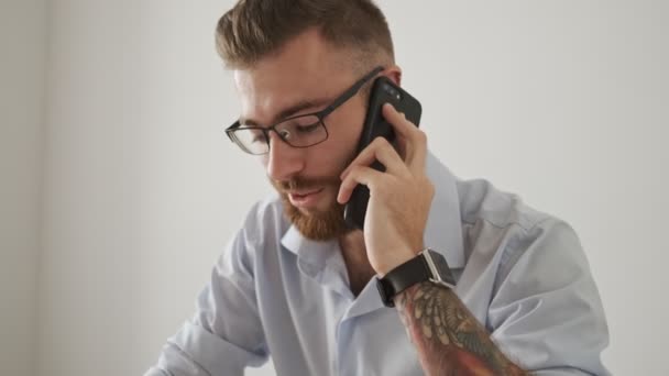 Atractivo Joven Empresario Con Anteojos Está Hablando Por Teléfono Mientras — Vídeos de Stock