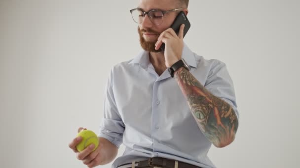 Atrakcyjny Młody Mężczyzna Okularach Trzyma Piłkę Tenisową Podczas Rozmowy Przez — Wideo stockowe