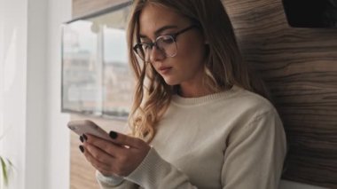 Güzel bir genç bayanın yakın çekim görüntüsü sabah mutfakta telefonla konuşuyor.