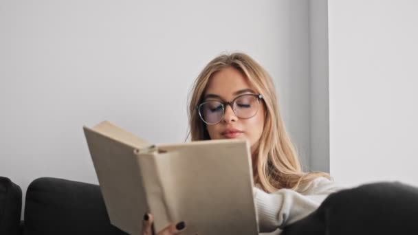 Een Mooie Jonge Vrouw Leest Een Boek Terwijl Woonkamer Zit — Stockvideo