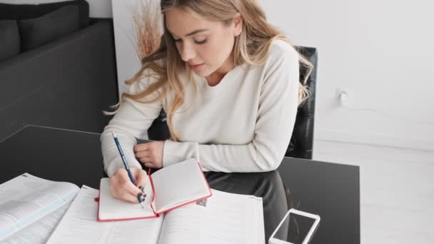 Een Geconcentreerde Jonge Blonde Vrouw Het Schrijven Van Oefeningen Tijdens — Stockvideo