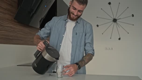 魅力的な若い男は家で台所でお茶を作る — ストック動画