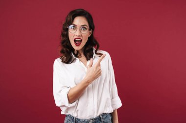 Şok olmuş genç bir kadının görüntüsü kırmızı duvar arkasında izole bir şekilde poz vermesi şaşırttı..