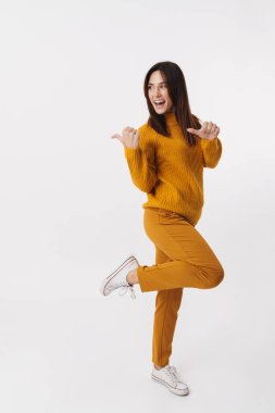 Güzel, esmer, yetişkin bir kadının beyaz arka planda izole edilmiş telif alanını gösteren ve gülümseyen tam boy görüntüsü.