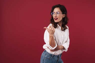 Kırmızı duvar arkasında yalnız poz veren neşeli ve güzel bir kadının görüntüsü..