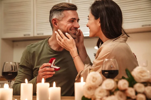 图为一个快乐的成年人在家里的烛光晚餐中 带着订婚戒指向他的女朋友求婚 — 图库照片