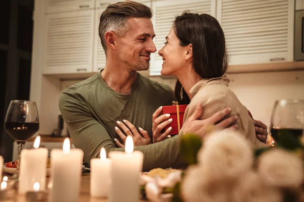 图片说明在浪漫的烛光晚餐中 快乐的成年人把礼物盒送给他的女朋友 — 图库照片