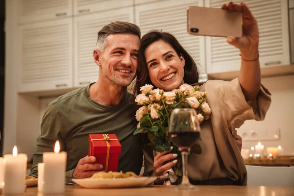 Obraz Szczęśliwy Kaukaski Para Biorąc Selfie Zdjęcie Kwiatami Podczas Romantycznej — Zdjęcie stockowe