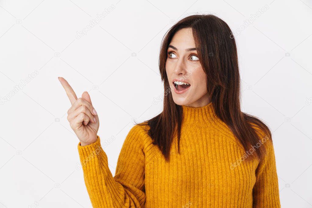 Image of beautiful brunette adult woman wearing sweater smiling and pointing finger aside at copyspace isolated over white background