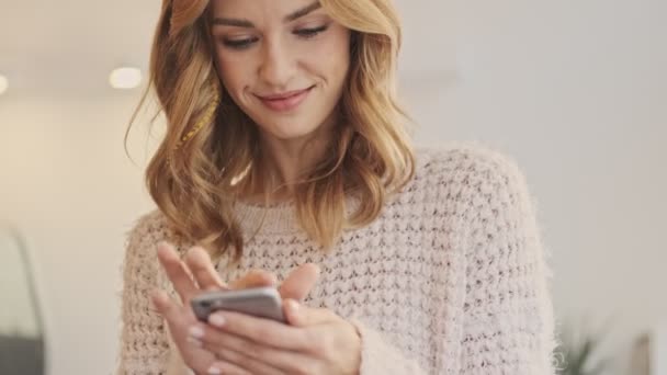 Una Mujer Sonriente Soñadora Positiva Está Mirando Teléfono Inteligente Mientras — Vídeos de Stock