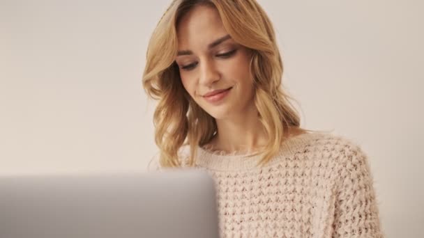一位年轻而快乐的女士正在用她的银色笔记本电脑工作 然后看着白色房间里的摄像机 — 图库视频影像