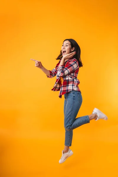 Photo Amazed Young Woman Jumping Pointing Finger Aside Isolated Yellow — Stock Photo, Image