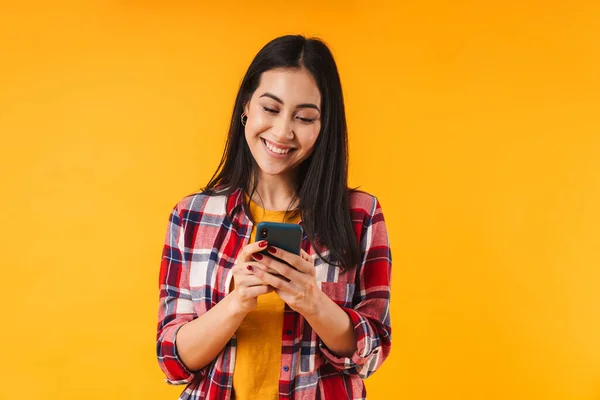 Photo Cheerful Brunette Woman Smiling While Using Cellphone Isolated Yellow — Stock Photo, Image
