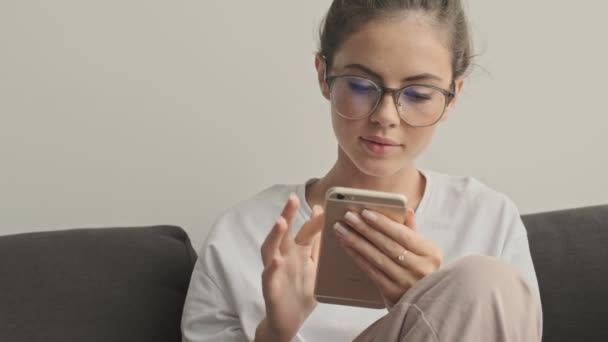 Zadowolony Ładna Brunetka Kobieta Okularach Pomocą Smartfona Podczas Siedzenia Kanapie — Wideo stockowe
