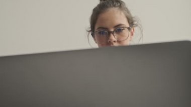 Gözlüklü güzel esmer kadın evdeki kanepede otururken dizüstü bilgisayar kullanıyor.