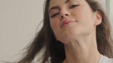 Neşeli, güzel, esmer kadının yakın görüntüsü. Göz kırpıyor ve evdeki kameraya bakıyor.