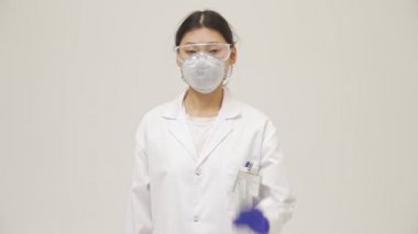 Genç Asyalı negatif doktor kadın, beyaz duvar zemininden izole edilmiş steril üniforma ölçüm sıcaklığı ile temassız termometre ile.