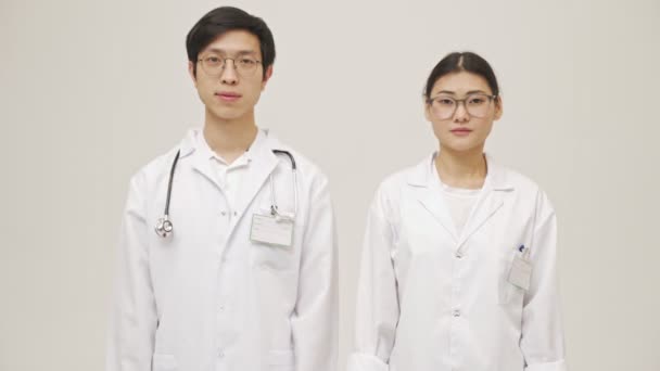 身穿无菌制服的情绪激动的年轻亚洲医生在白墙背景上显得孤立无援 — 图库视频影像