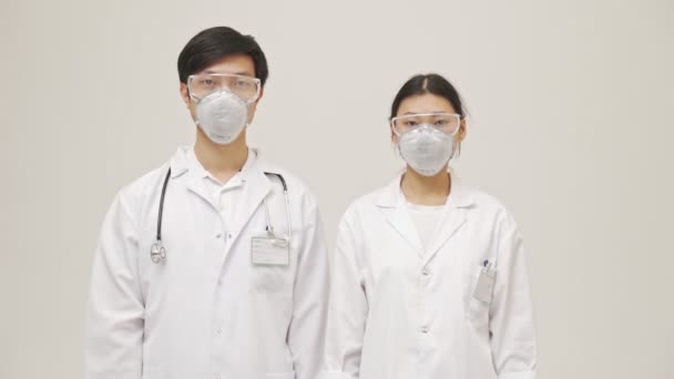 年轻的亚洲严肃的医生穿着无菌制服 在白种人的背景上被隔离开来 — 图库视频影像