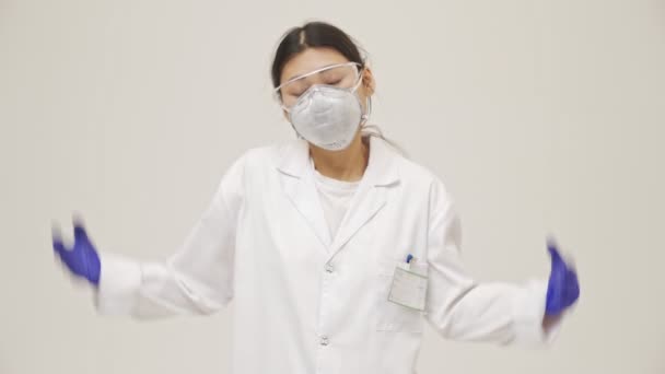 年轻的亚裔困惑的没有保险的医生女人穿着无菌的制服被隔离在白墙后面 — 图库视频影像
