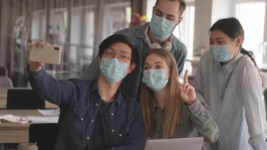 Genç, olumlu iş adamları ofiste Coronavirus yüzünden maske takarak selfie çekiyorlar..