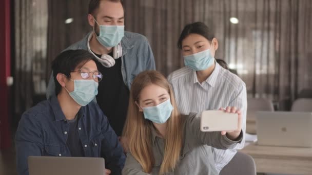 若い正の幸せなビジネスの人々同僚室内オフィスで自画撮り着用マスクのためのコロナウイルスショーOkジェスチャー — ストック動画