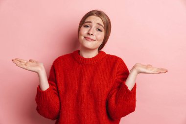 Kafası karışmış genç bir kadının pembe duvar arkasında yalnız poz vermesi..