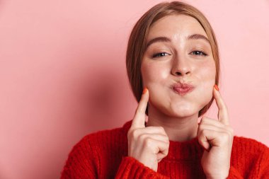 Pembe duvar arkasında yalnız poz veren genç ve güzel bir kadın resmi.