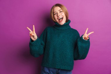 Mor duvar arkasında izole edilmiş, barış jesti gösteren mutlu, genç bir kadın görüntüsü.