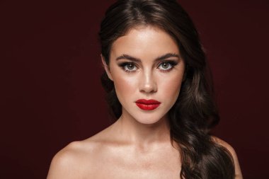 Burgonya arka planında izole edilmiş kameraya bakan güzel makyajlı muhteşem üstsüz kadın görüntüsü.