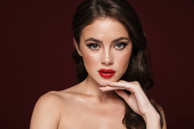 Burgonya arka planında izole edilmiş kameraya bakan güzel makyajlı muhteşem üstsüz kadın görüntüsü.