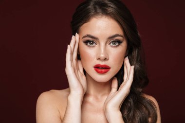 Beyaz tişörtsüz, güzel makyajlı bir kadının Burgonya arka planında izole edilmiş kameraya bakışları.