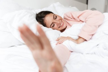Yatak odasında pijama giyen, ellerini uzatan neşeli, genç bir kız.