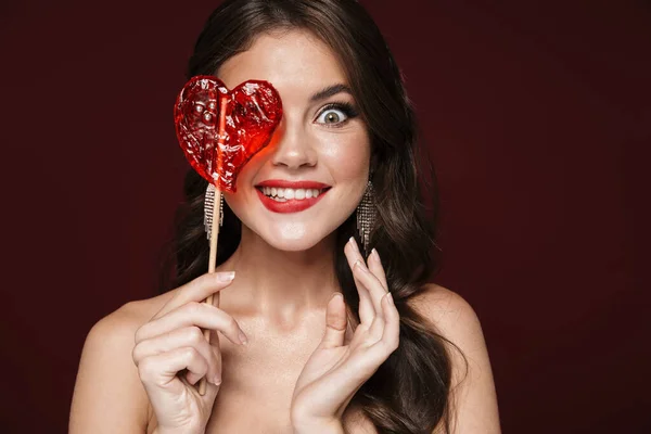 Image Amusing Shirtless Woman Wearing Earrings Grimacing Holding Candy Isolated — Stock Photo, Image