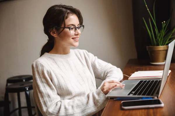 カフェで勉強しながらノートパソコンを使って眼鏡をかける若い美人白人女性の姿 — ストック写真