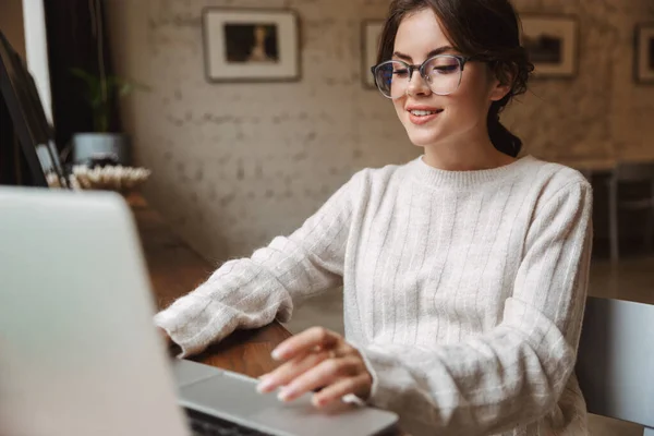カフェで勉強しながらノートパソコンを使って眼鏡をかける若い美人白人女性の姿 — ストック写真
