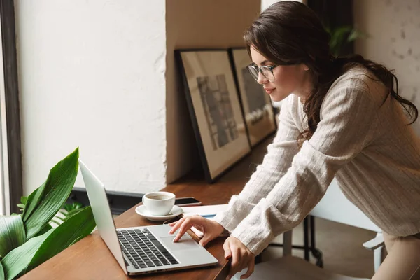 カフェで勉強しながらノートパソコンを使って眼鏡をかける若い美人白人女性の姿 — ストック写真