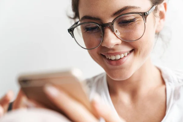 Imagen Mujer Concentrada Anteojos Sonriendo Usando Teléfono Celular Sala Estar —  Fotos de Stock