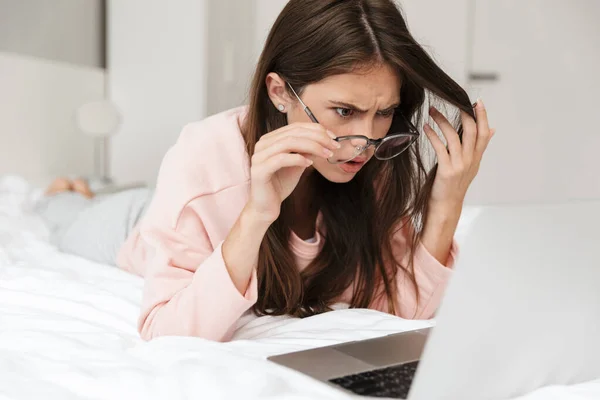 Confuso Linda Menina Vestindo Pijama Deitado Cama Quarto Usando Computador — Fotografia de Stock