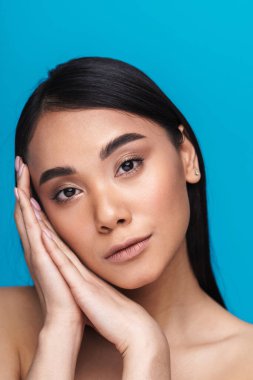 Asyalı genç bir kadının mavi duvar arkasında izole edilmiş pozu..