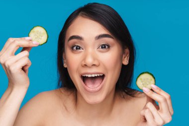 Asyalı şaşkın, iyimser genç bir kadının mavi duvar arkasında limon çığlığıyla poz vermesi..