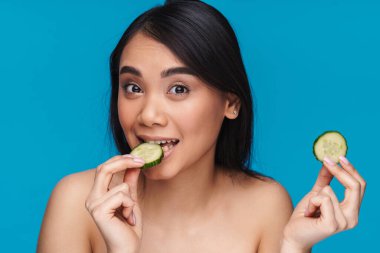 Mutlu, iyimser, güzel bir kadının mavi duvar arkasında limonlu poz verdiği bir fotoğraf..