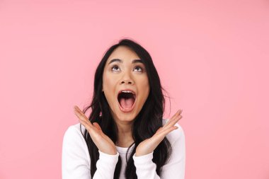 Genç esmer Asyalı kadın resmi. Günlük kıyafetler içinde çığlık atıyor ve pembe arka planda yalnız bir şekilde yukarı bakıyor.