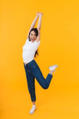 Sarı arka planda, günlük kıyafetler giymiş, gülümseyen ve eğlenen esmer bir kadın resmi.