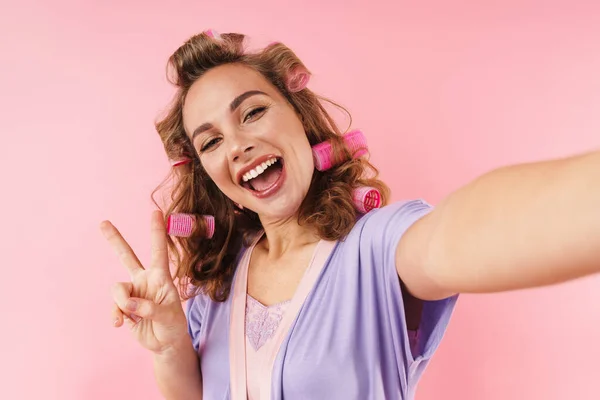 Imagem Jovem Mulher Sorridente Curlers Gesticulando Sinal Paz Tomar Selfie — Fotografia de Stock