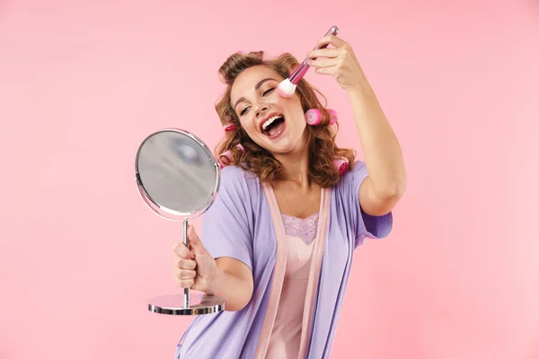 照片中的年轻女子穿着毛刷用粉刷和镜子隔离在粉红背景 — 图库照片