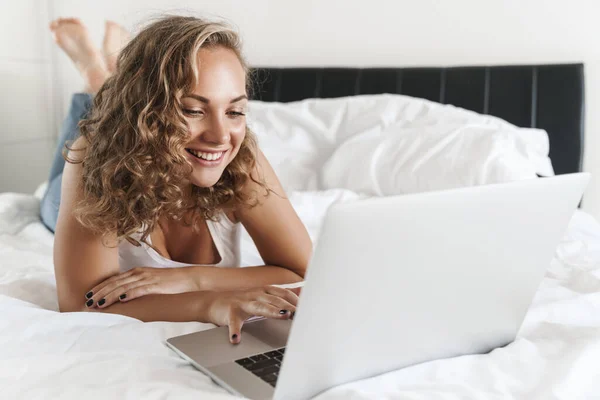 Счастливая Красивая Молодая Блондинка Лежит Кровати Используя Ноутбук — стоковое фото