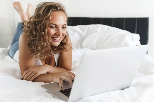 Счастливая Красивая Молодая Блондинка Лежит Кровати Используя Ноутбук — стоковое фото
