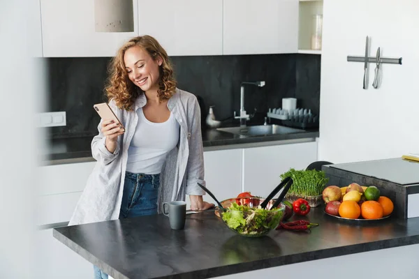 Lächelnde Junge Frau Lässiger Kleidung Mit Handy Während Sie Sich — Stockfoto