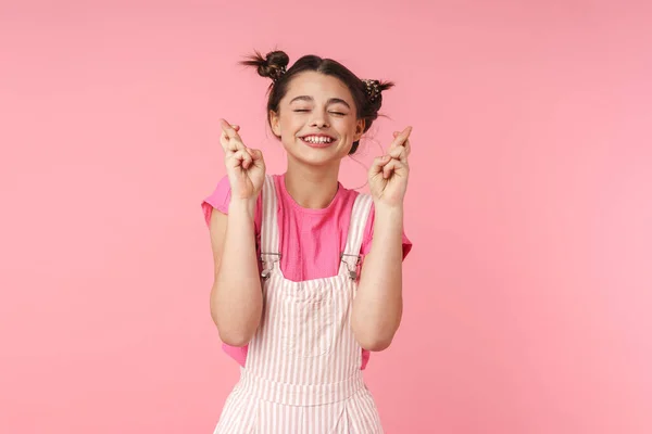 照片上 一个滑稽的女孩 戴着鼻环 手握着手指 为好运而祈祷 在粉色的背景下 独自微笑 — 图库照片